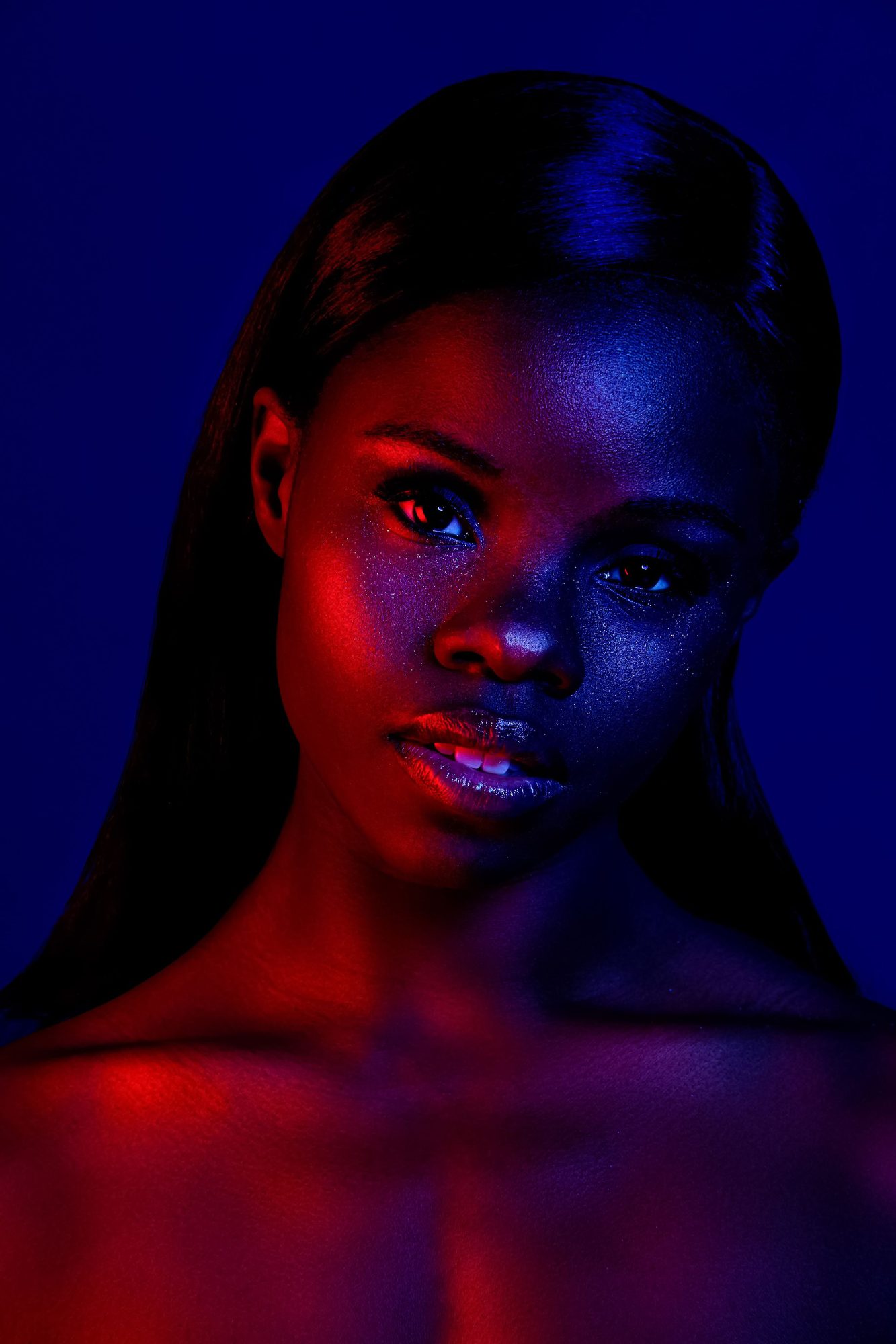 Portrait of a woman lit in red and blue on a dark blue ground